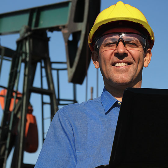 Man in hardhat in front of pump jack