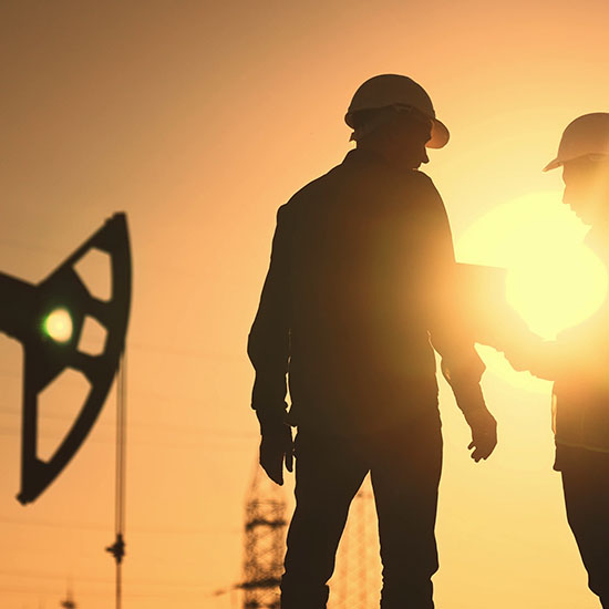 Two men in front of a pump jack