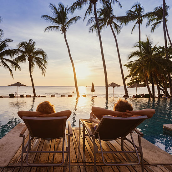 Couple relaxing by a pool on a tropical beach